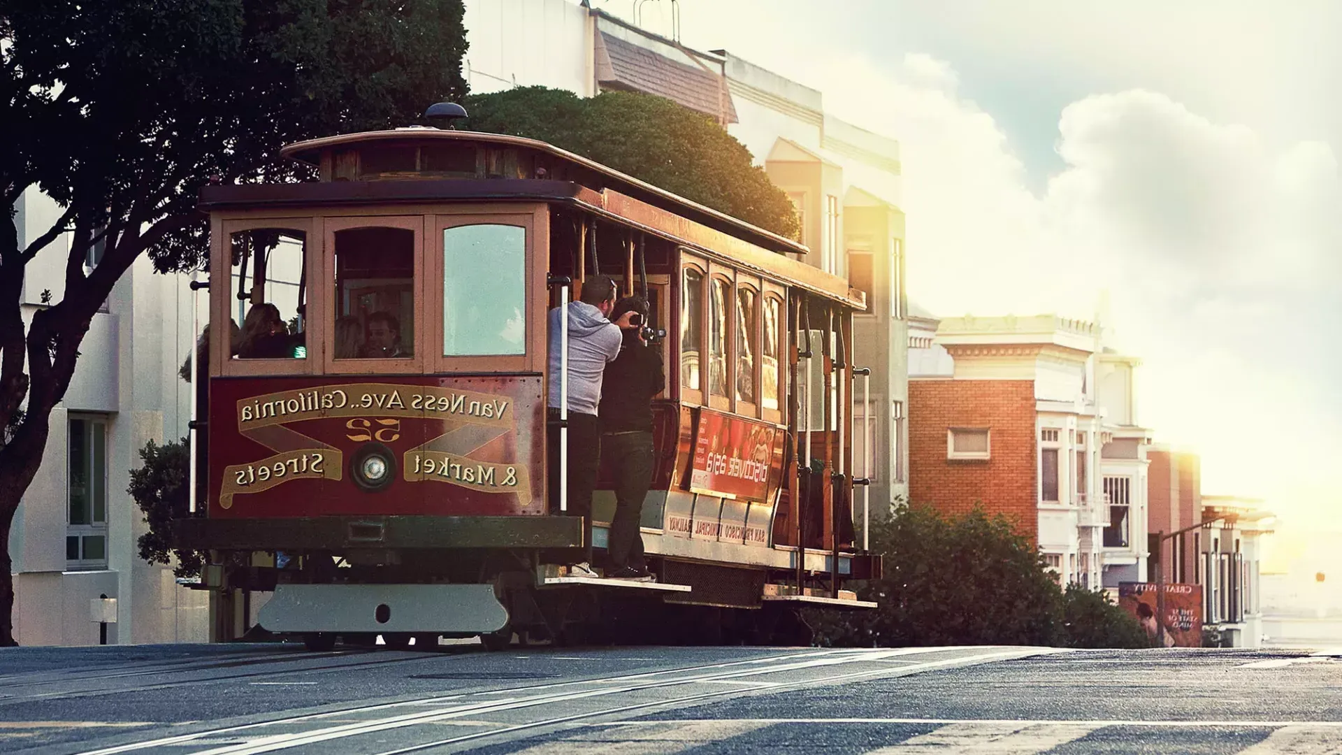 Eine Seilbahn fährt um einen Hügel in San Francisco, während die Passagiere aus dem Fenster schauen.